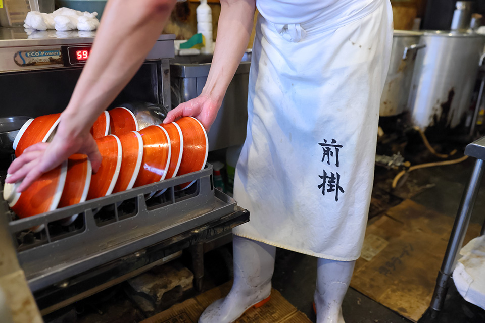 ラーメンのどんぶりを食洗機につっこむ横尾健太さん