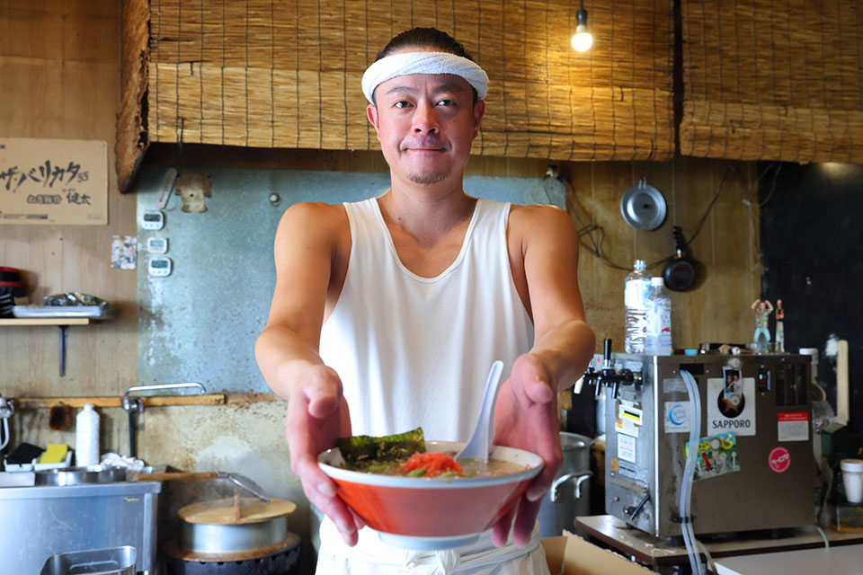 ラーメン健太の店主横尾健太さんがらーめんを提供している写真