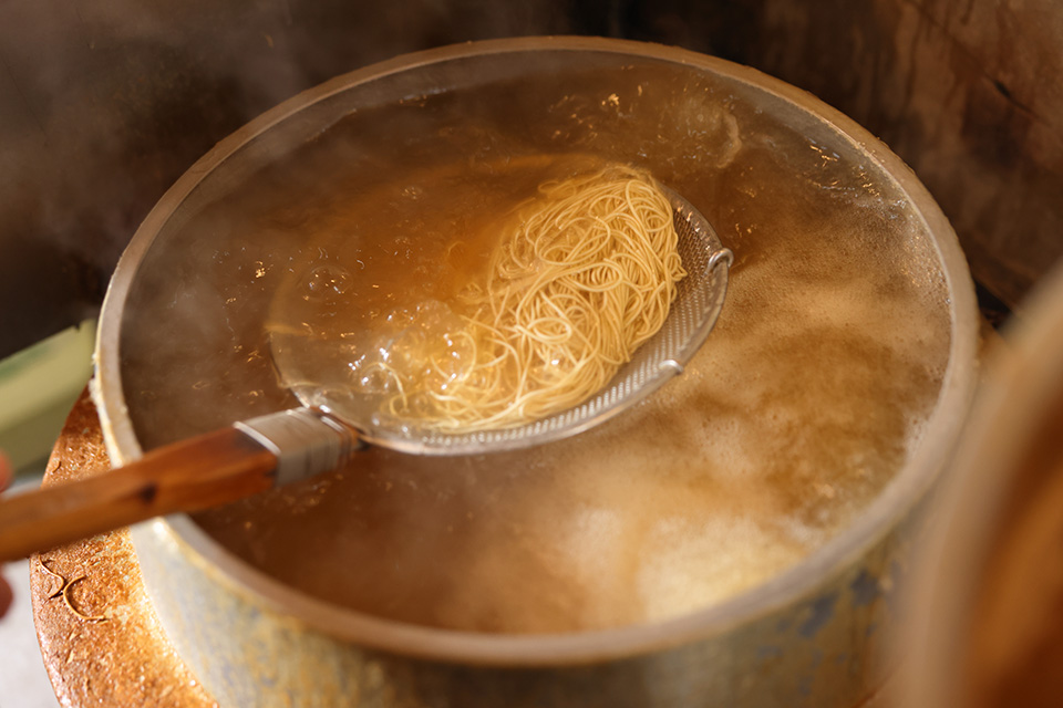 鍋で麺を茹でている健太さん